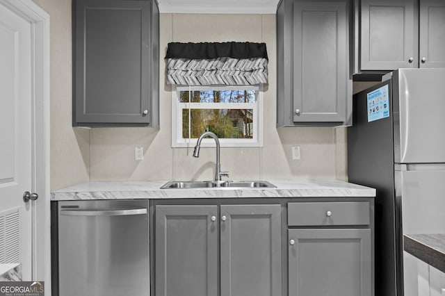 kitchen featuring light countertops, stainless steel appliances, a sink, and gray cabinetry