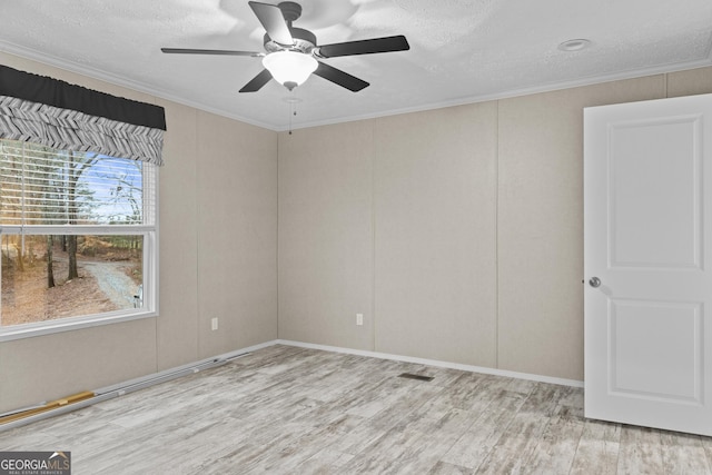 spare room featuring ornamental molding, light wood-style flooring, a textured ceiling, and a ceiling fan