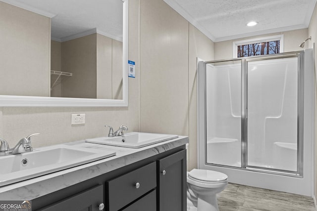 full bathroom featuring ornamental molding, a shower with shower door, a sink, a textured ceiling, and wood finished floors