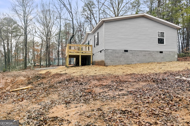 view of property exterior with crawl space and a deck