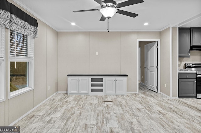 interior space featuring light wood finished floors, crown molding, a ceiling fan, and a wealth of natural light