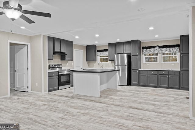 kitchen with light wood-style floors, a kitchen island, stainless steel appliances, gray cabinetry, and under cabinet range hood