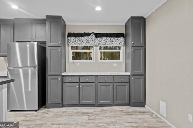 kitchen with light wood-style flooring, freestanding refrigerator, light stone countertops, gray cabinets, and recessed lighting