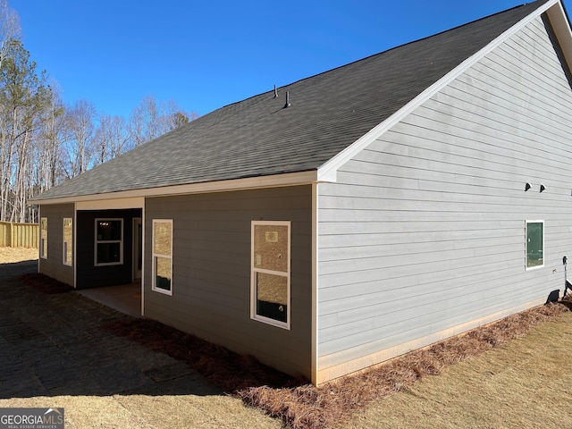 view of home's exterior featuring a patio area and roof with shingles