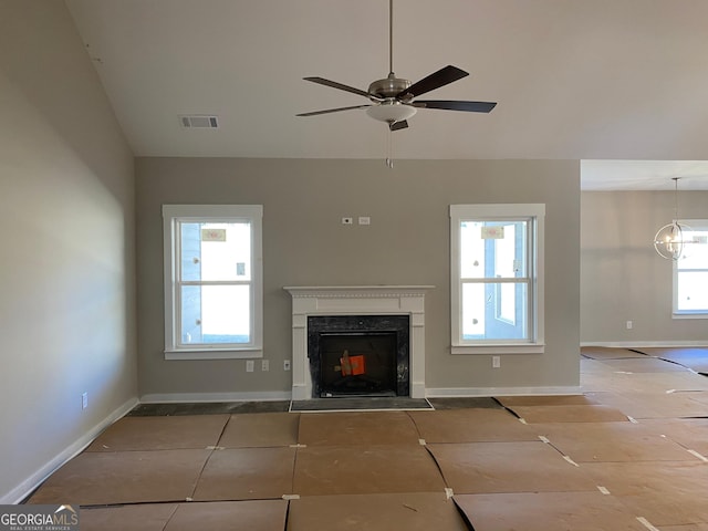 unfurnished living room featuring visible vents, a fireplace, baseboards, and ceiling fan with notable chandelier