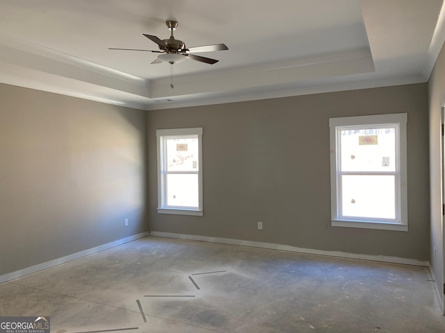 empty room featuring baseboards, a tray ceiling, and concrete flooring