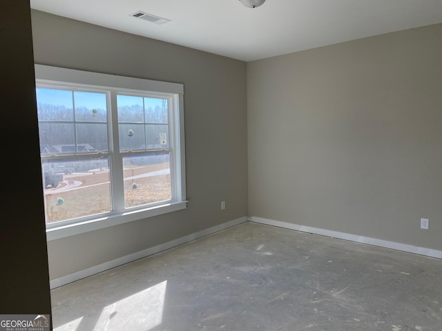 spare room featuring plenty of natural light, visible vents, baseboards, and unfinished concrete floors