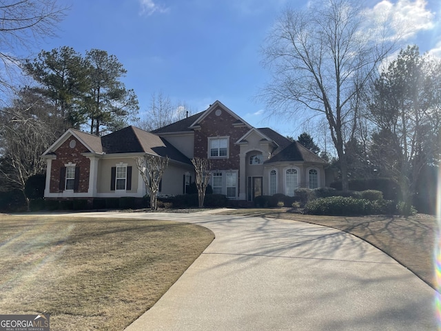 view of front of house featuring stucco siding, brick siding, and driveway