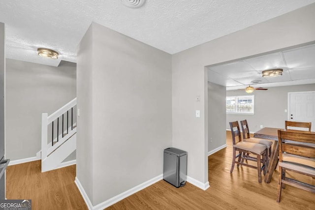 interior space with light wood-style floors, stairs, baseboards, and a textured ceiling