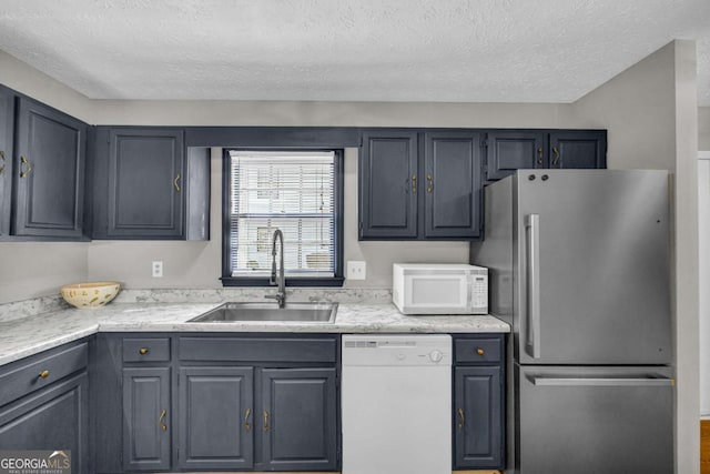 kitchen featuring light countertops, gray cabinetry, a sink, a textured ceiling, and white appliances