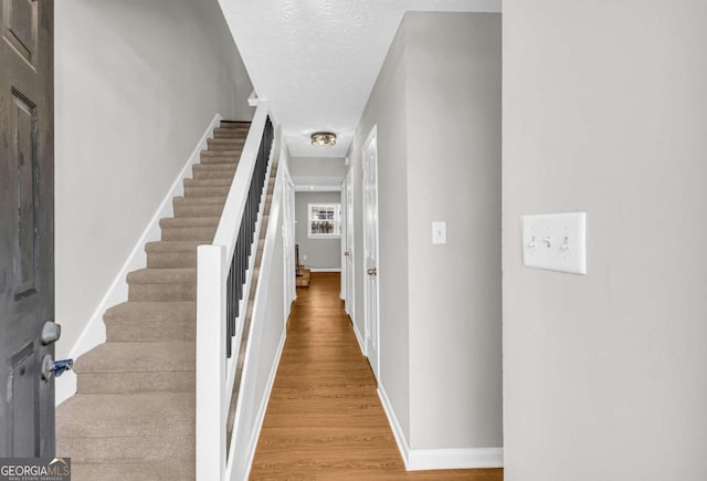 interior space with light wood-style floors, stairway, baseboards, and a textured ceiling