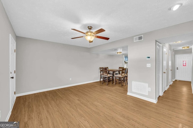 interior space with baseboards, visible vents, ceiling fan, and light wood finished floors