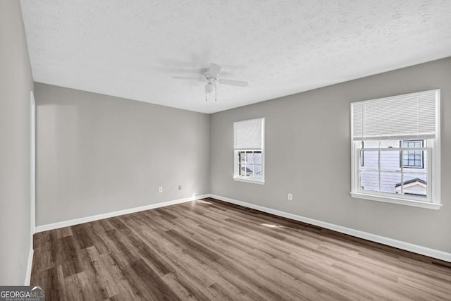 unfurnished room with a healthy amount of sunlight, baseboards, and wood finished floors