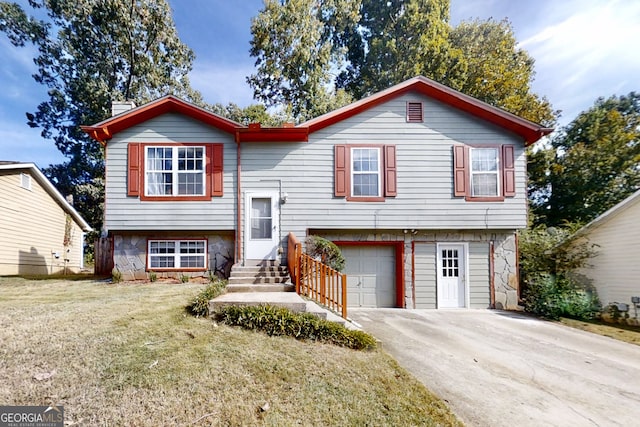 raised ranch with a garage, driveway, a chimney, and a front yard