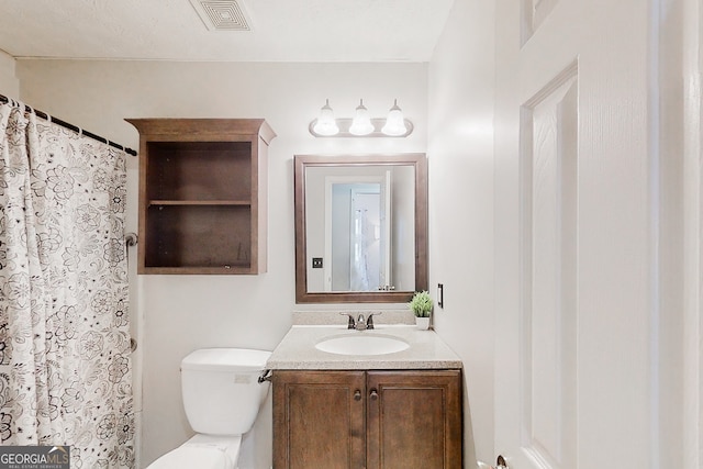 bathroom with toilet, vanity, and visible vents