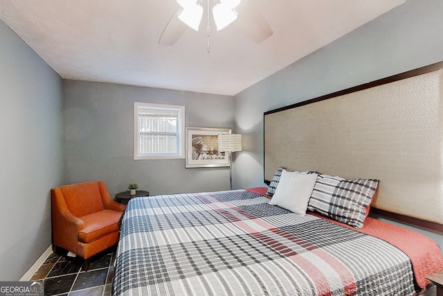 bedroom with dark tile patterned floors, a ceiling fan, and baseboards