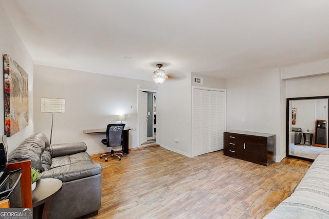 living area with light wood-style flooring, visible vents, and baseboards