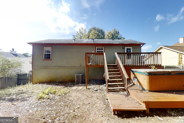 rear view of house with a deck, cooling unit, fence, stairway, and a hot tub