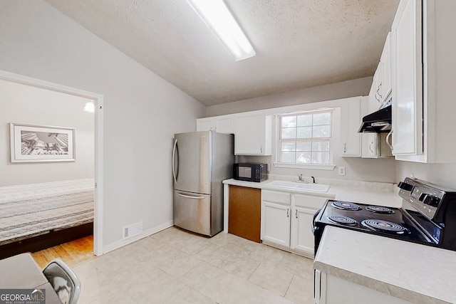 kitchen with electric stove, light countertops, freestanding refrigerator, a sink, and black microwave