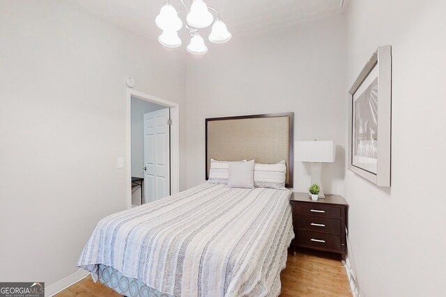 bedroom featuring light wood-style floors, baseboards, and a chandelier