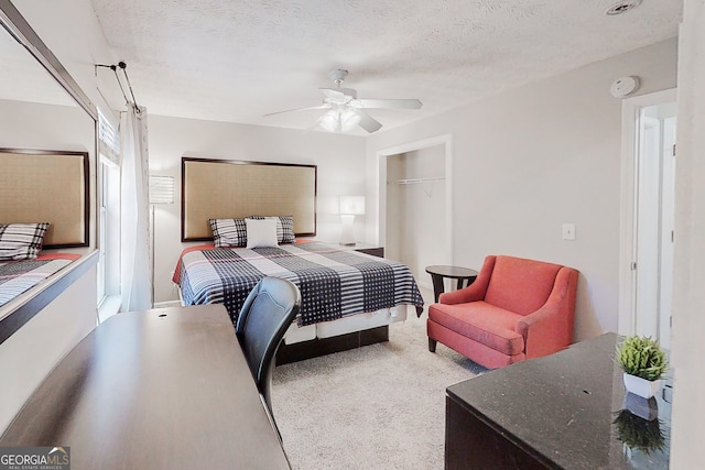 carpeted bedroom with a textured ceiling, ceiling fan, and a closet