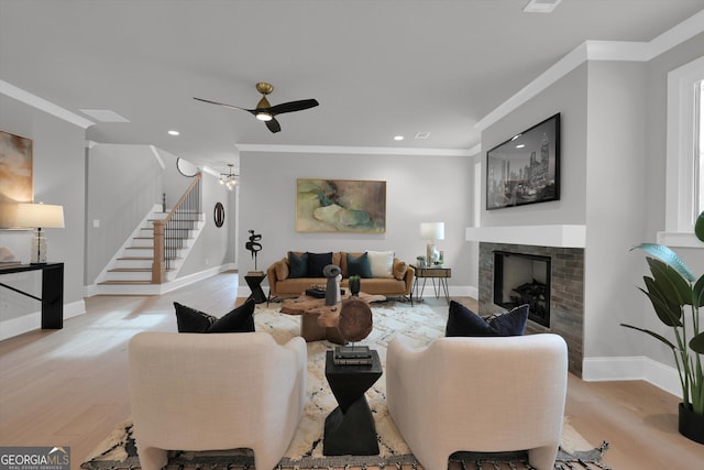 living room with light wood-type flooring, stairway, a fireplace, and crown molding