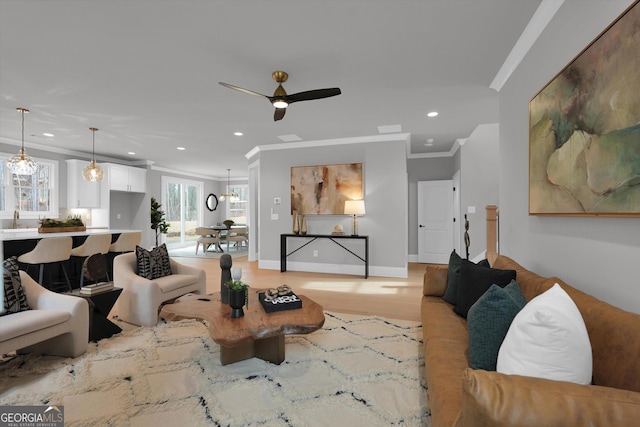 living area featuring recessed lighting, ornamental molding, light wood-style floors, ceiling fan, and baseboards