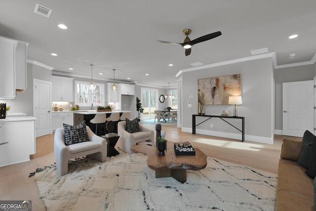 living room with visible vents, ornamental molding, light wood-style flooring, and recessed lighting