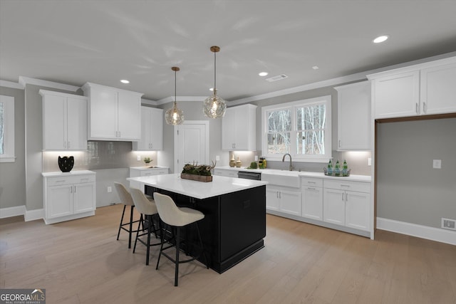 kitchen featuring baseboards, a kitchen bar, white cabinetry, and a center island