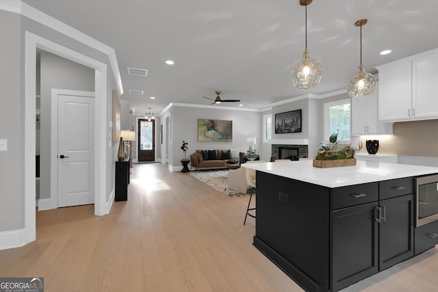 kitchen with visible vents, white cabinets, light countertops, and ornamental molding