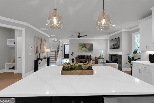 kitchen featuring white cabinets, a kitchen island, ornamental molding, and a fireplace