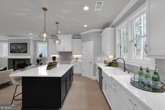 kitchen featuring a fireplace, light countertops, visible vents, open floor plan, and white cabinetry