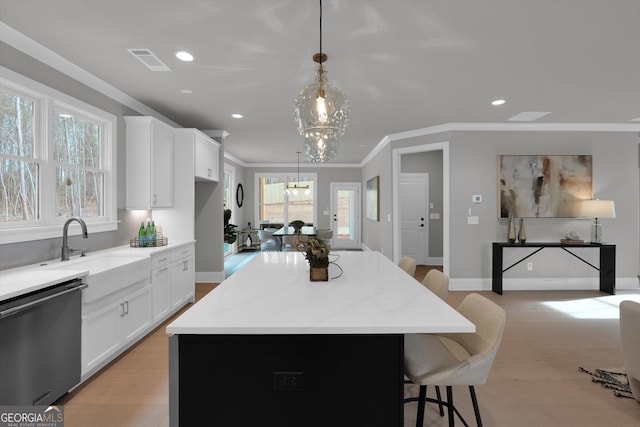 kitchen with a breakfast bar area, a kitchen island, a sink, visible vents, and stainless steel dishwasher