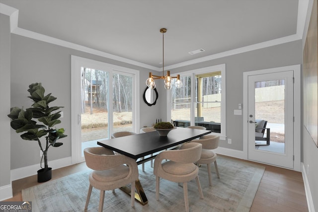 dining space with a notable chandelier, light wood finished floors, visible vents, ornamental molding, and baseboards