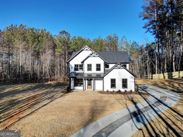 view of front of property featuring a shingled roof, a standing seam roof, metal roof, and driveway