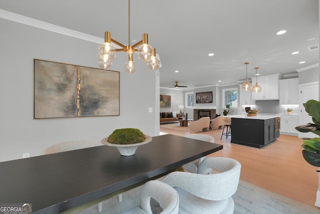 dining room featuring a fireplace, recessed lighting, light wood-style floors, ornamental molding, and a ceiling fan