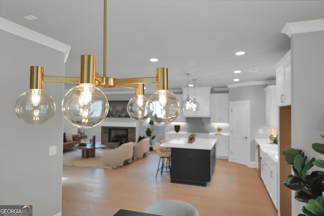 kitchen featuring a breakfast bar area, light wood-style flooring, white cabinets, light countertops, and a center island