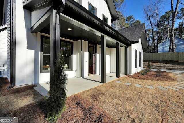 view of side of property featuring a shingled roof, fence, and board and batten siding