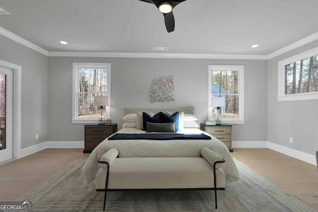 bedroom featuring multiple windows, visible vents, wood finished floors, and ornamental molding