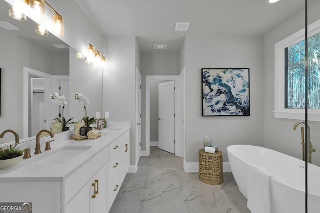 full bathroom featuring marble finish floor, a soaking tub, a sink, and visible vents