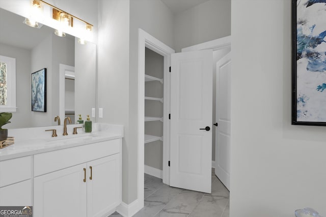 full bathroom featuring marble finish floor, vanity, baseboards, and a spacious closet