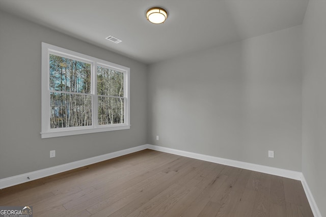 unfurnished room featuring visible vents, baseboards, and wood finished floors