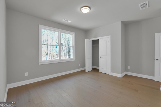 unfurnished bedroom featuring visible vents, baseboards, and wood finished floors