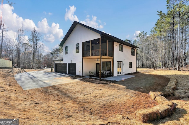 exterior space featuring driveway, a sunroom, ceiling fan, an attached garage, and a patio area