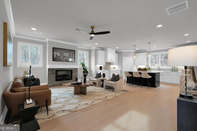 living area with a wealth of natural light, visible vents, a fireplace, and light wood finished floors