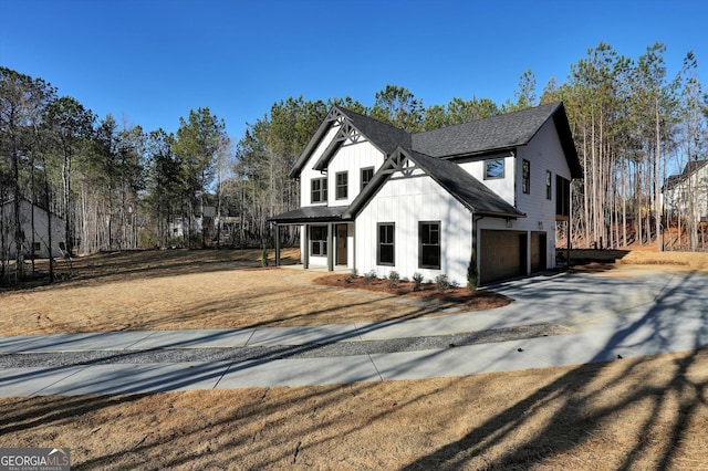 view of front of house with concrete driveway, a shingled roof, board and batten siding, and an attached garage