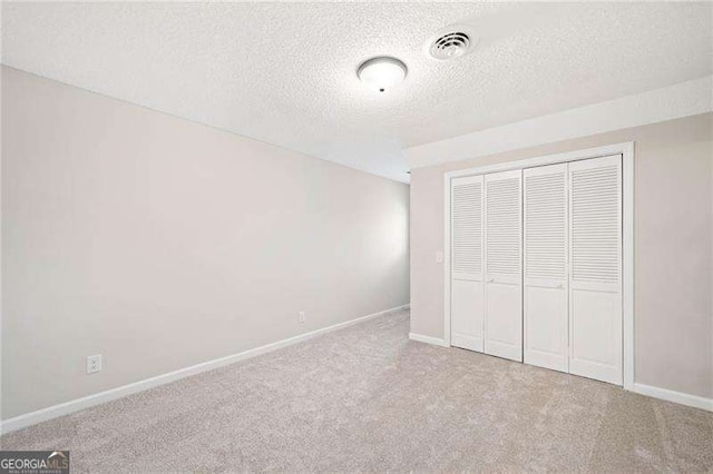 unfurnished bedroom with carpet floors, baseboards, visible vents, and a closet