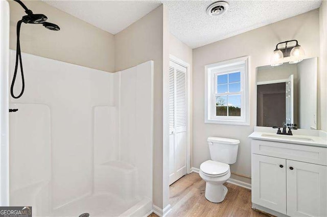 bathroom with a closet, visible vents, toilet, a shower stall, and vanity