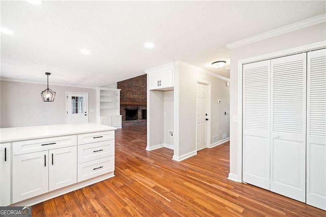 kitchen with built in shelves, white cabinets, light countertops, ornamental molding, and decorative light fixtures