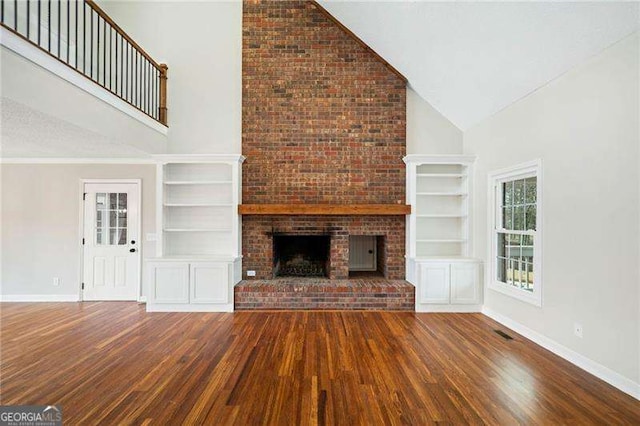 unfurnished living room featuring a fireplace, high vaulted ceiling, and wood finished floors